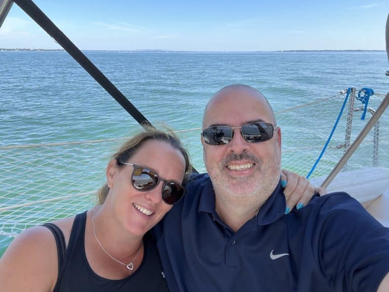 Couple souriant sur un bateau, vue sur la mer.